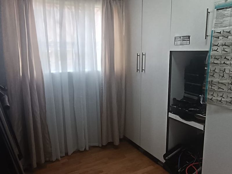 A bedroom featuring built-in cupboards and laminate flooring, currently utilized as a home gym space.