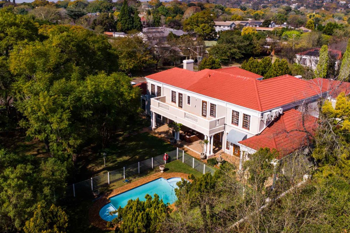 Aerial view of a large two-story residence featuring a red tile roof, a private swimming pool, and a spacious rear garden.