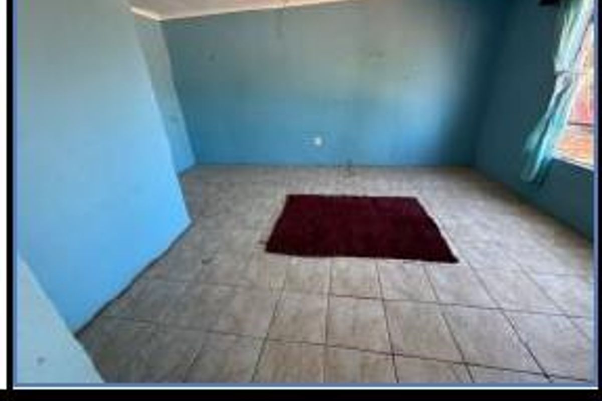 A spacious living room featuring tiled flooring and blue painted walls, offering a blank canvas for personalization.