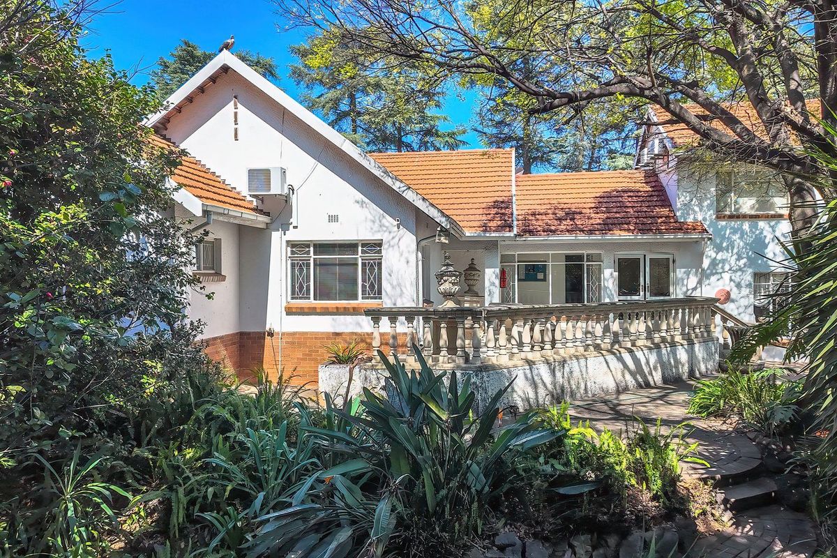 Rear view of the office property featuring a paved patio area, traditional terracotta roof tiles, and established garden surroundings.