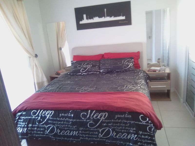 A bedroom featuring tiled flooring and built-in bedside tables with integrated mirrors.