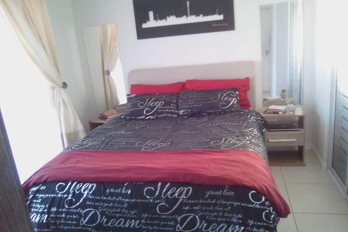 A bedroom featuring tiled flooring and built-in bedside tables with integrated mirrors.
