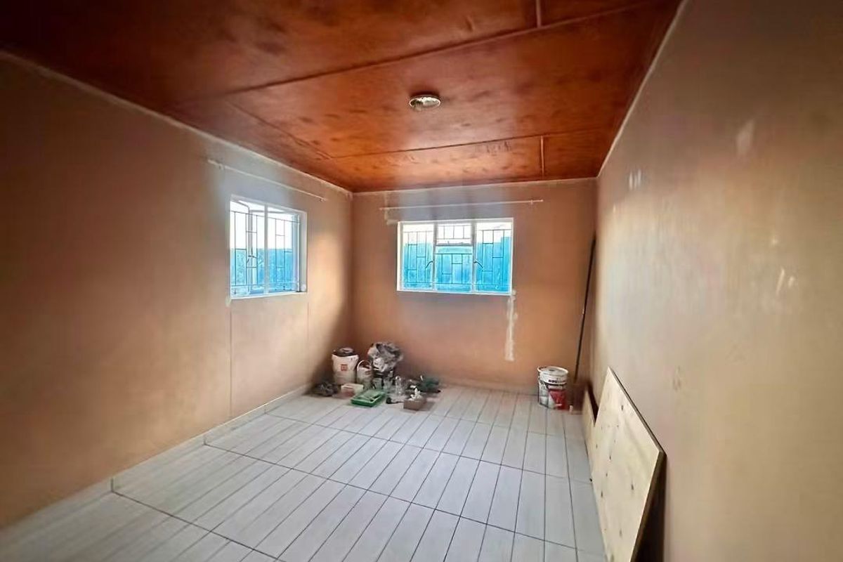 An empty bedroom featuring tiled flooring and a timber ceiling, currently undergoing minor renovations with unfinished wall surfaces.