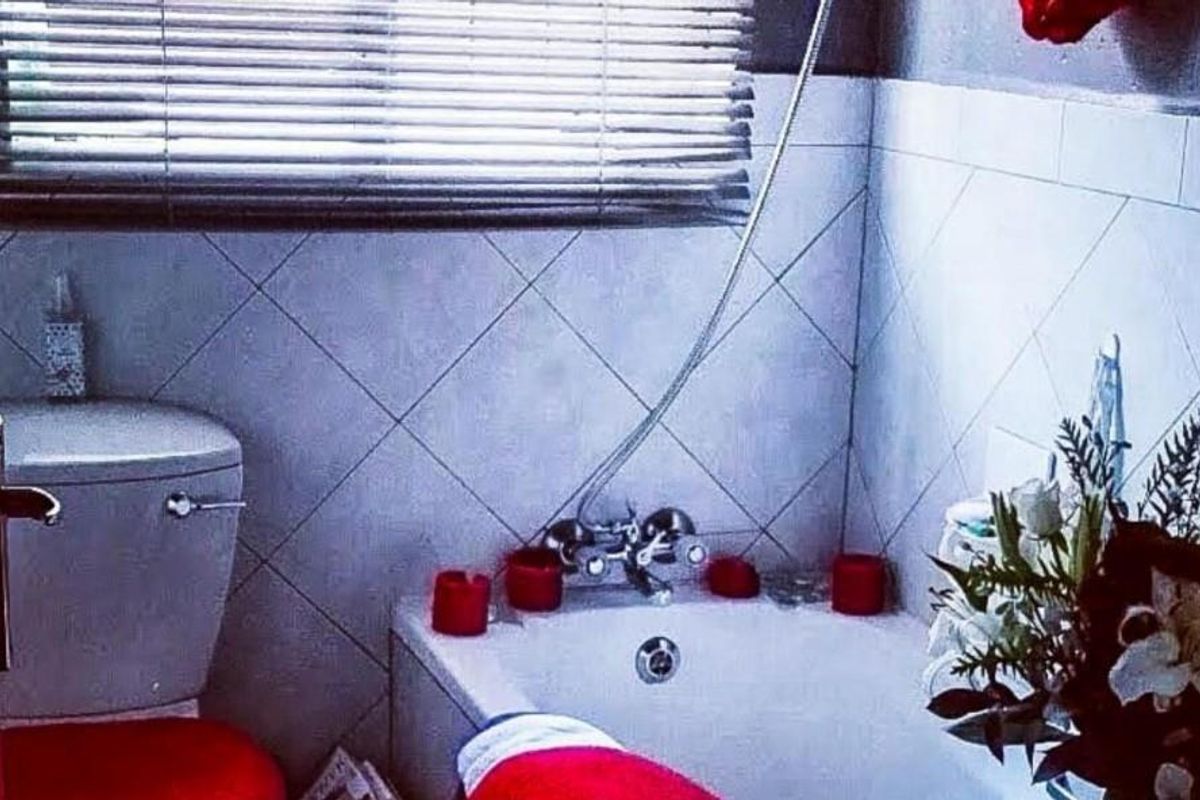 A functional bathroom featuring a bathtub with a handheld shower mixer, a standard toilet, and tiled wall finishes.