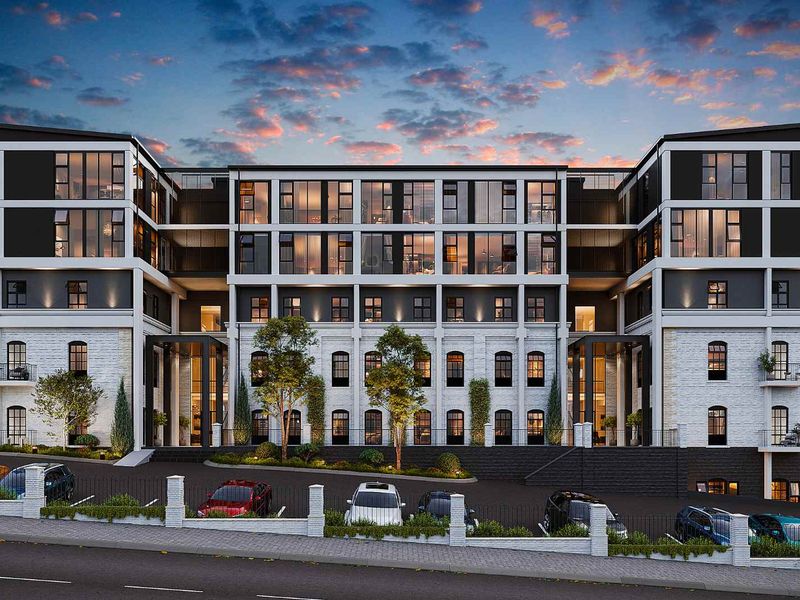 A modern multi-story apartment building exterior featuring a contemporary facade with large windows, balconies, and a paved driveway at sunset.