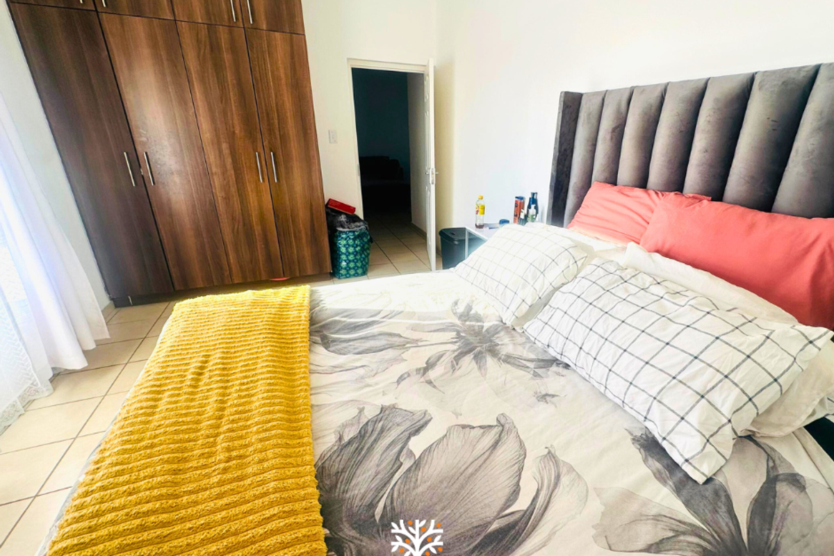 A well-lit bedroom featuring built-in wooden cupboards and tiled flooring, providing ample storage space and a clean, functional layout.