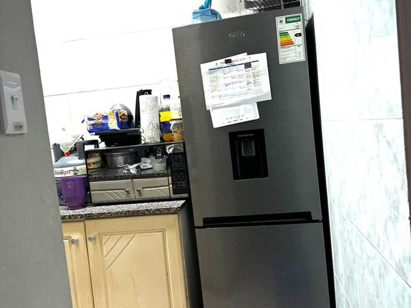 A compact kitchen area featuring tiled walls, base cabinetry with granite countertops, and built-in microwave space, showing signs of wear.