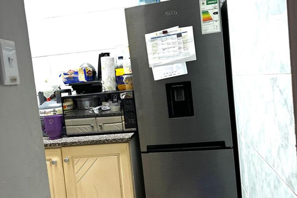 A compact kitchen area featuring tiled walls, base cabinetry with granite countertops, and built-in microwave space, showing signs of wear.