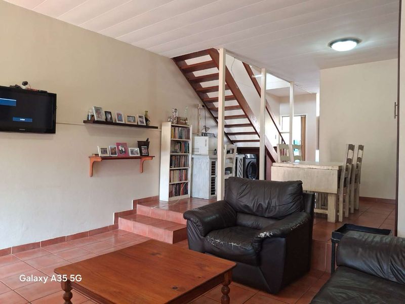 Open plan living and dining area featuring a wooden staircase, tiled flooring, and a raised platform layout.