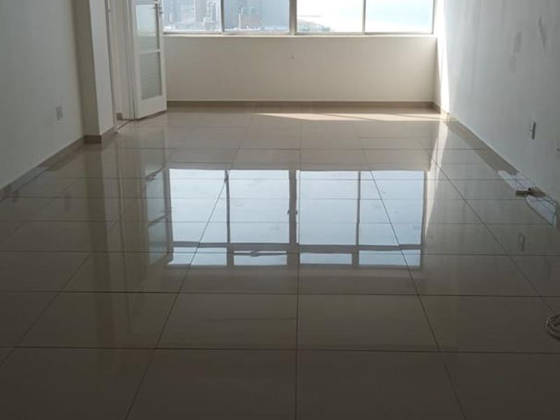 Spacious, empty living area featuring polished tiled flooring, a ceiling fan, and large windows providing natural light and an urban view.