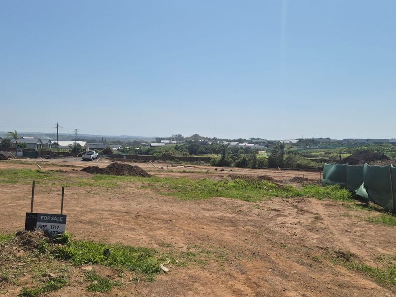 A wide-angle view of a vacant residential plot featuring cleared land and perimeter fencing, overlooking the surrounding neighborhood landscape.