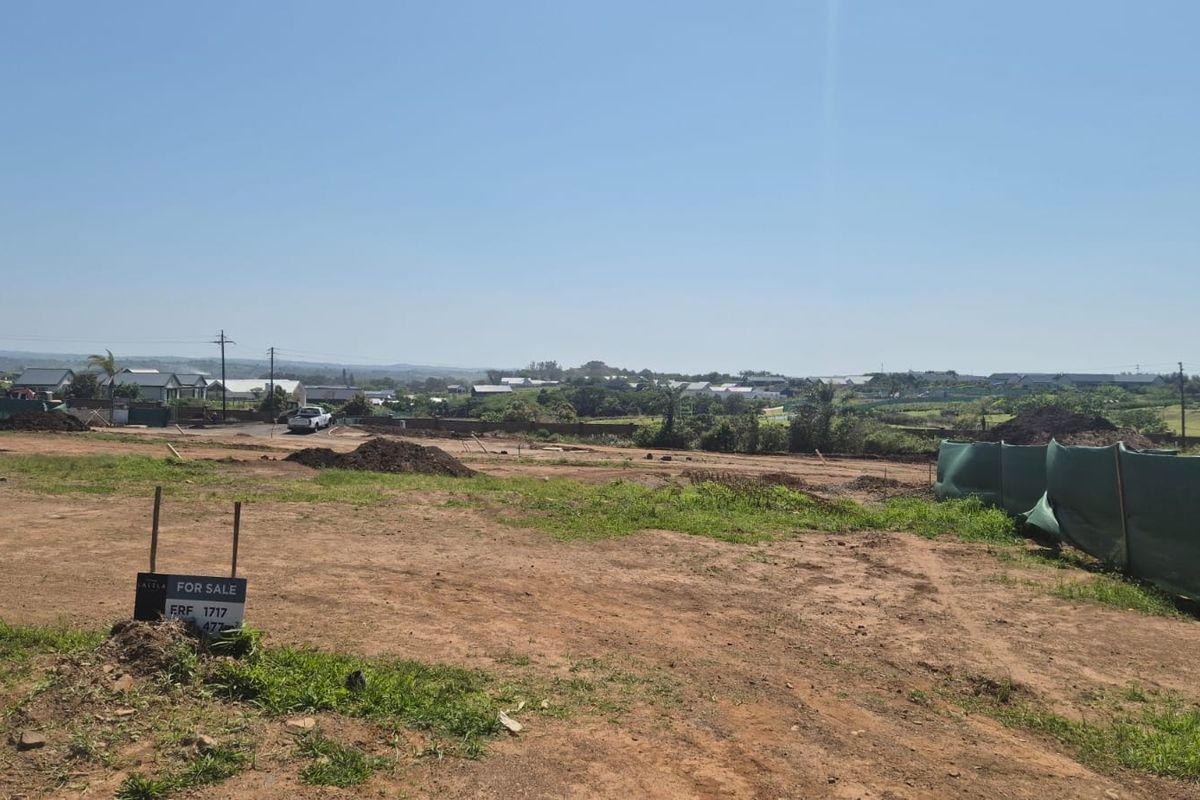 A wide-angle view of a vacant residential plot featuring cleared land and perimeter fencing, overlooking the surrounding neighborhood landscape.