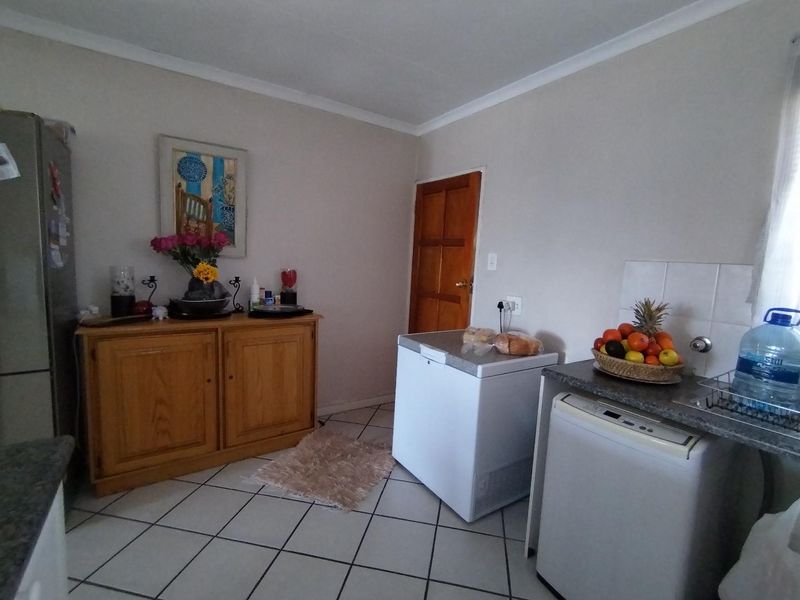 A functional kitchen area featuring tiled flooring, a tiled backsplash, and a sink, providing a practical space for daily culinary tasks.