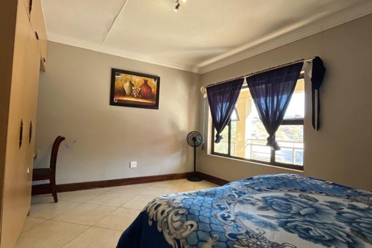 A bedroom featuring tiled flooring, built-in wooden cupboards, and a ceiling-mounted light fixture, offering a functional living space.
