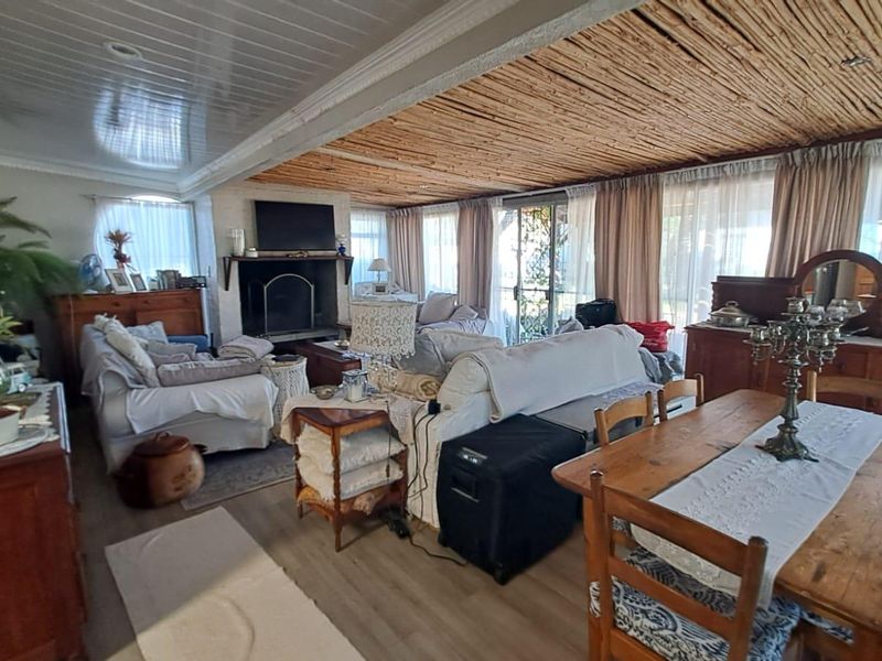 Spacious open-plan living and dining area featuring a fireplace, laminate flooring, and a unique timber ceiling with direct access to the outdoor space.