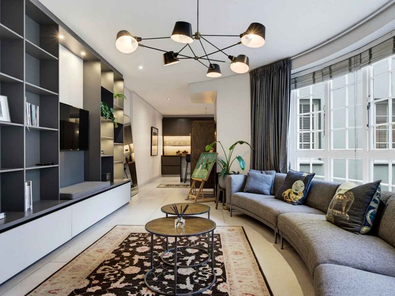 Modern living room featuring a large built-in shelving unit, tiled floors, and ample natural light from a multi-pane window.