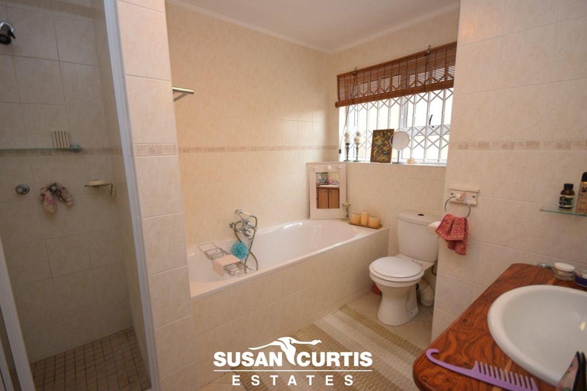 A functional bathroom featuring a built-in bathtub, separate shower enclosure, toilet, and a vanity basin with tiled finishes.