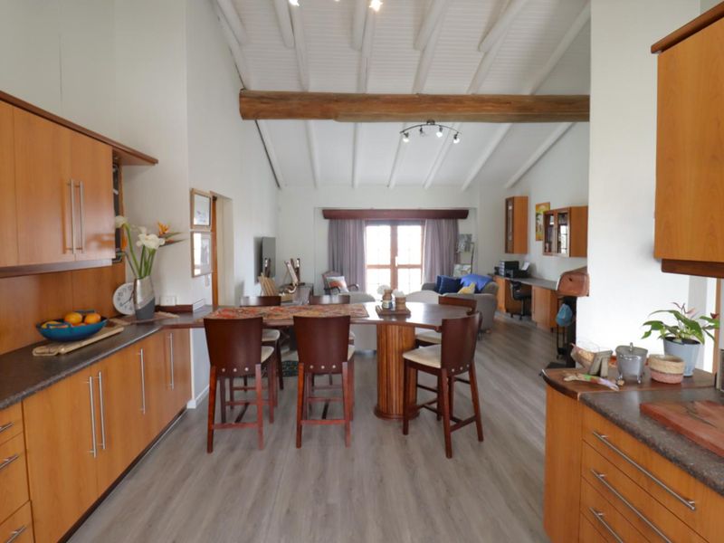 Open-plan living area featuring a kitchen with wooden cabinetry, a breakfast bar, and a spacious lounge area under a vaulted ceiling with exposed beams.