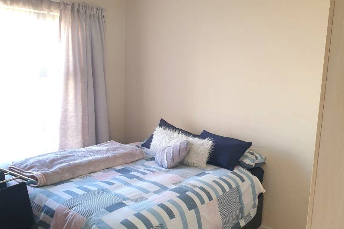 A standard bedroom featuring laminate flooring, a ceiling light fixture, and a built-in cupboard.