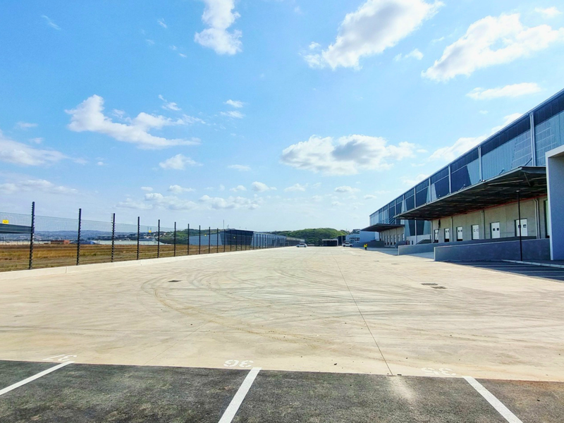 Spacious industrial concrete yard featuring multiple loading bays, perimeter security fencing, and ample maneuvering space for heavy vehicles.