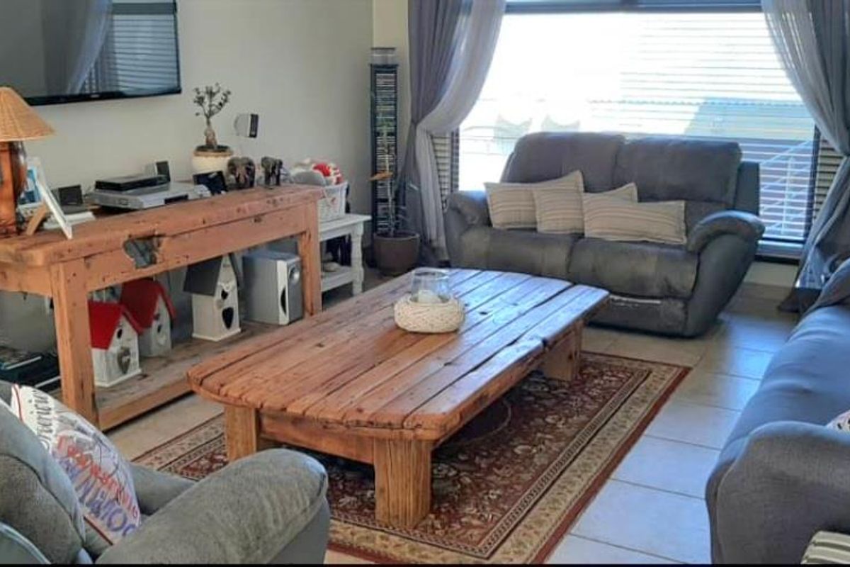 A comfortable living room featuring tiled flooring and large windows that provide natural light, creating a welcoming space for relaxation.