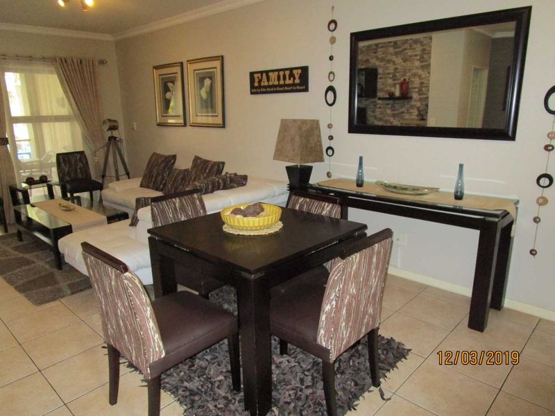 Open plan living and dining area featuring tiled flooring and access to a patio through a sliding glass door.