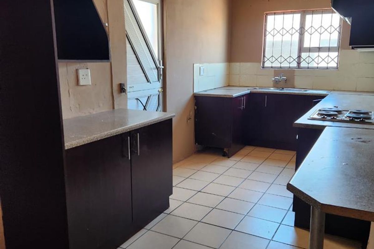 A functional kitchen featuring dark cabinetry, built-in hob, tiled flooring, and direct access to the exterior.