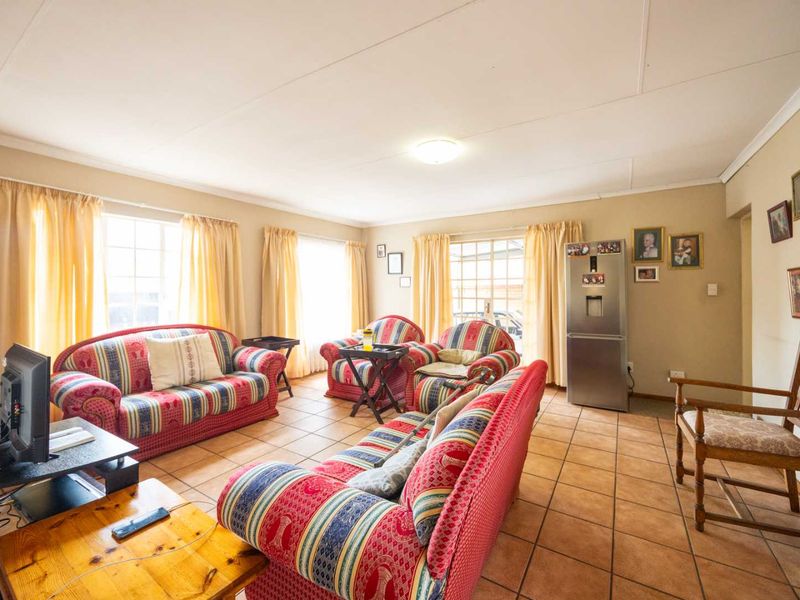 A spacious living room featuring tiled flooring and large windows that provide ample natural light, offering a comfortable and functional living space.