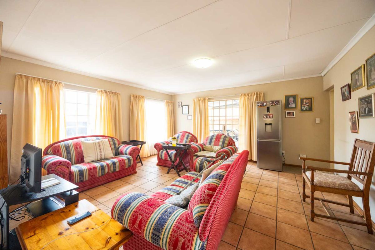 A spacious living room featuring tiled flooring and large windows that provide ample natural light, offering a comfortable and functional living space.