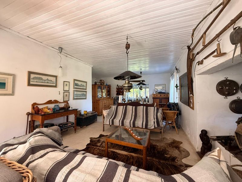 A rustic living room featuring a timber plank ceiling and a traditional fireplace, showcasing a dated interior with potential for modernization.