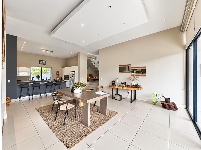 Spacious open-plan living and dining area featuring a modern kitchen with island, recessed ceiling lighting, and large sliding doors leading to the exterior.