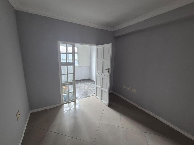 An empty bedroom featuring tiled flooring, decorative cornice, and a door leading to an adjacent balcony area.