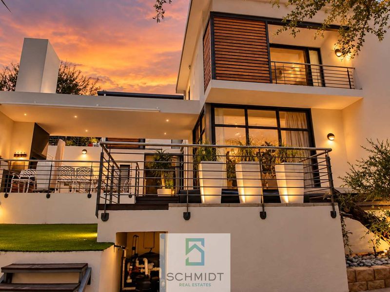 Modern multi-level townhouse rear elevation featuring a spacious balcony, patio area, contemporary architectural lighting, and high-quality finishes at dusk.