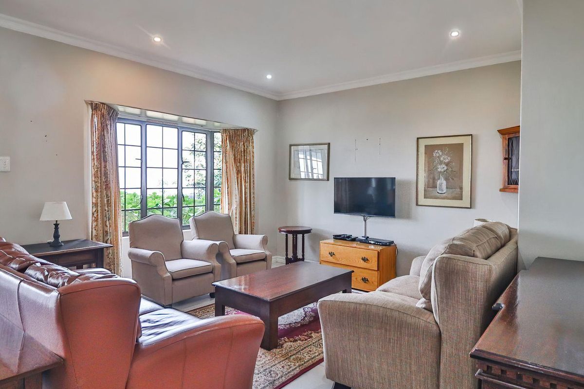 A comfortable living room featuring a large bay window, recessed ceiling lighting, and neutral wall finishes.