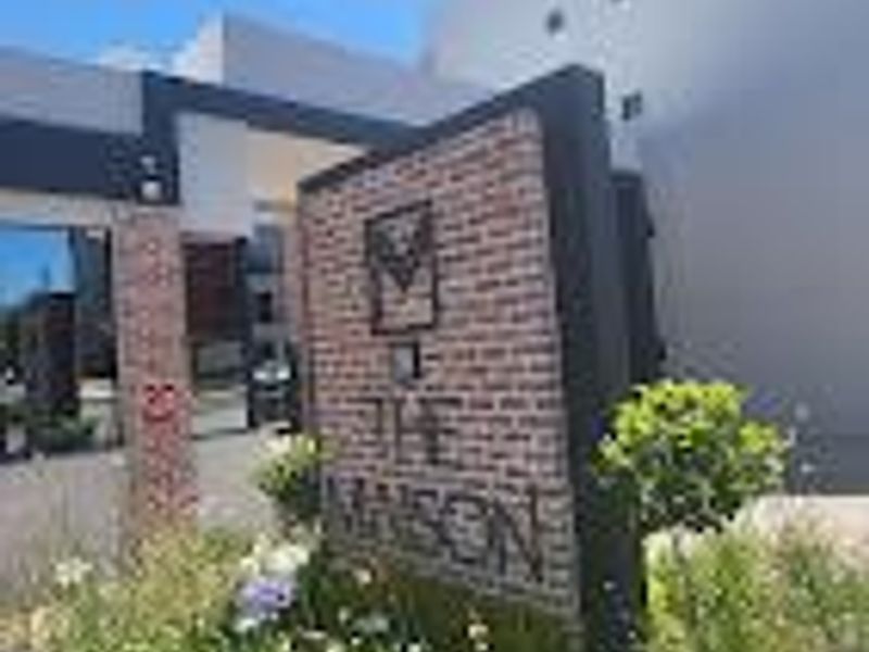 The entrance to The Mason apartment complex featuring a brick signage wall and secure gated access.
