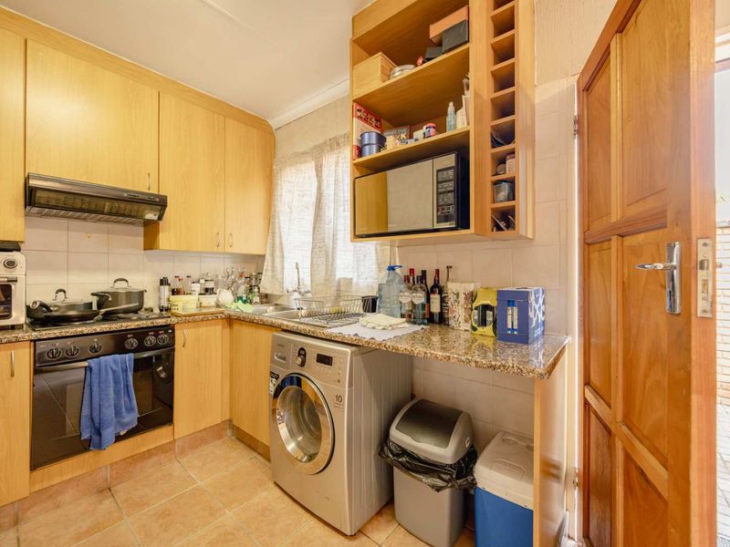Compact kitchen featuring light wood cabinetry, granite countertops, built-in oven, hob, and direct access to an outdoor area.