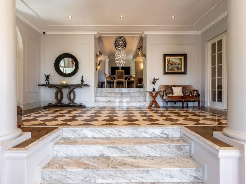 Grand entrance hall featuring elegant marble stairs, sophisticated checkered marble flooring, and high-end architectural detailing leading into the main living area.