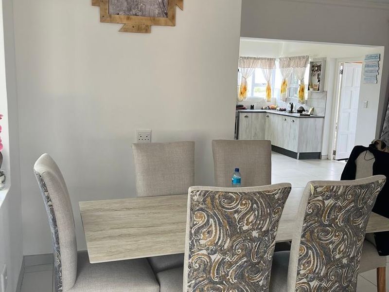Open plan dining area leading into a functional kitchen with tiled flooring and neutral cabinetry.