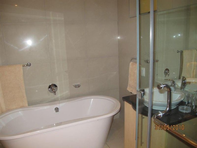 A bathroom featuring a freestanding bathtub, a vessel sink with a granite vanity top, and a glass-enclosed shower area with tiled walls.