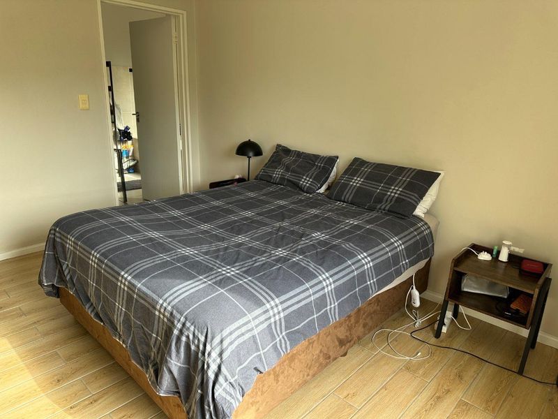 A functional bedroom featuring tiled flooring and neutral wall tones, providing a clean and simple space for rest.
