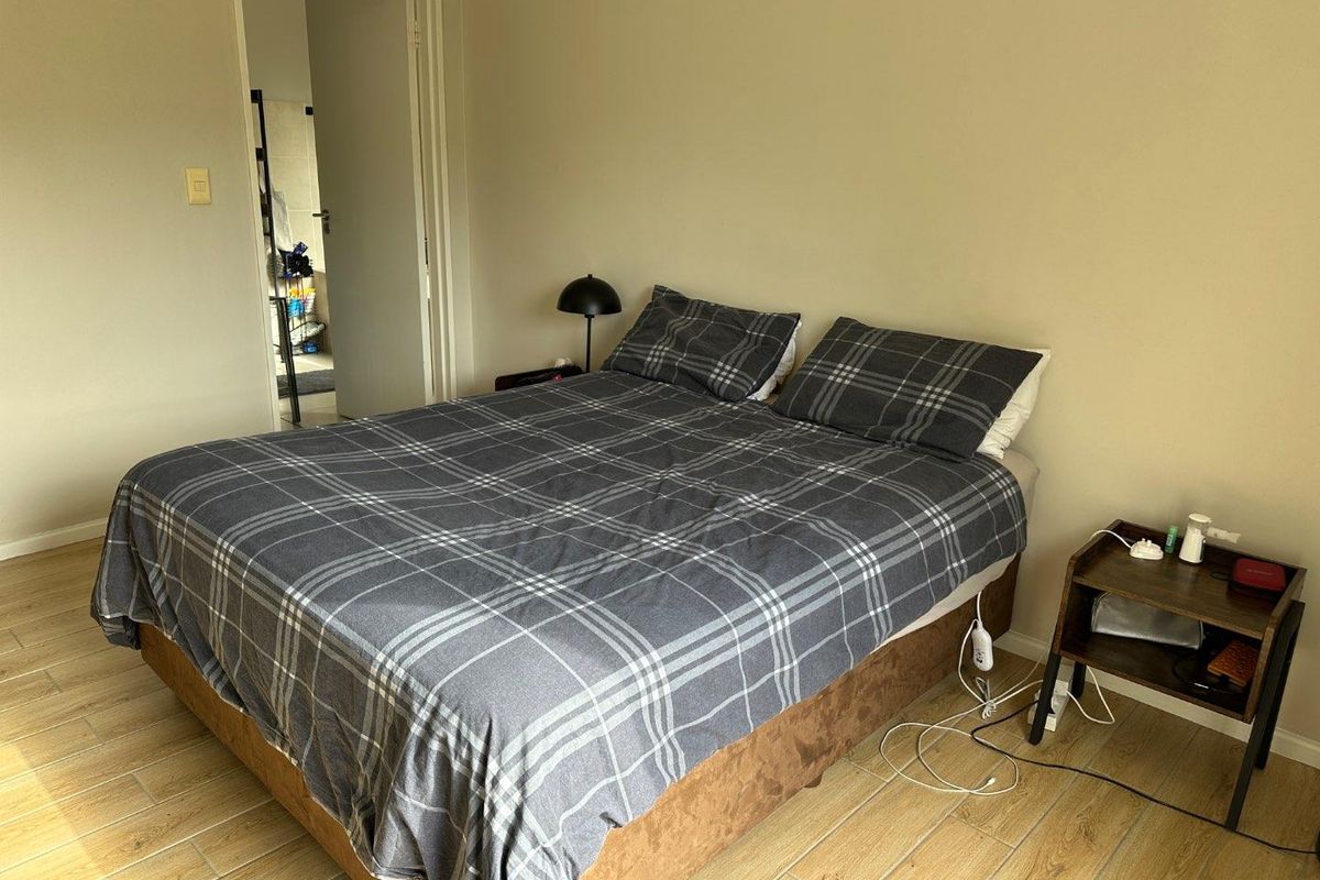 A functional bedroom featuring tiled flooring and neutral wall tones, providing a clean and simple space for rest.