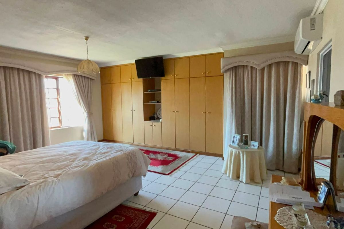 Spacious bedroom featuring extensive built-in wooden cabinetry, tiled flooring, and a wall-mounted air conditioning unit.