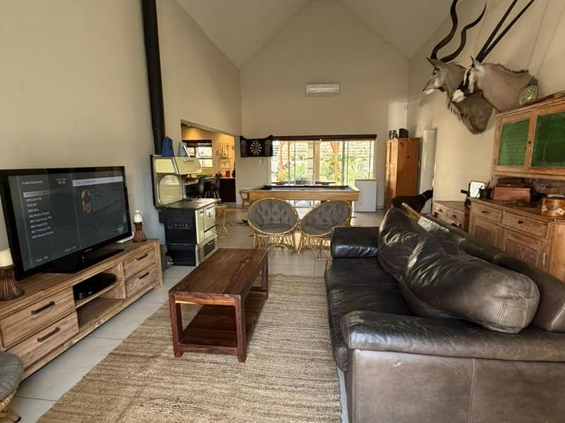 Spacious open-plan living area featuring a high vaulted ceiling, tiled flooring, and a prominent wood-burning stove, creating a comfortable and versatile living space.