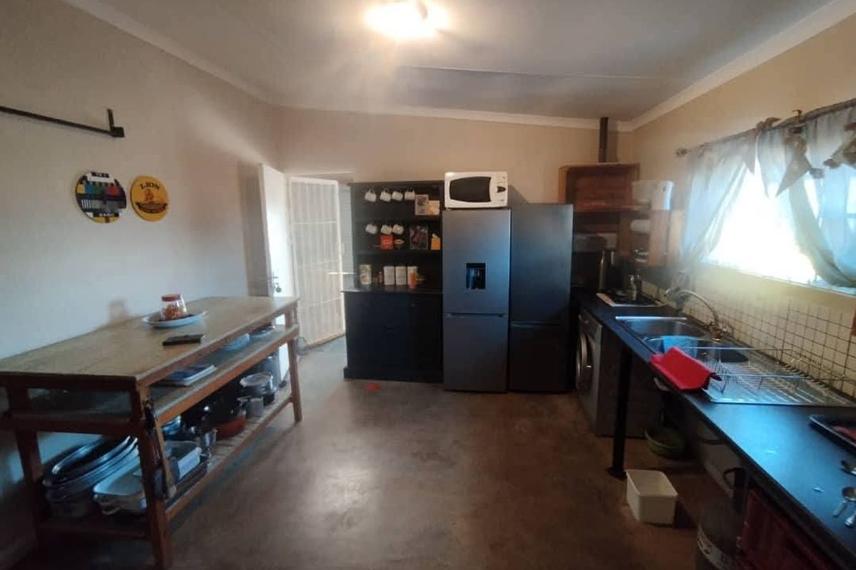 A functional kitchen area featuring a double sink, built-in cabinetry, and concrete flooring, providing a practical space for food preparation and utility tasks.