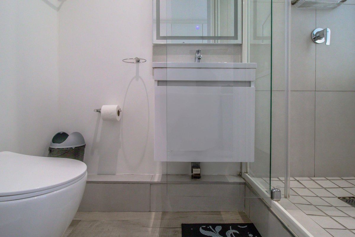 Modern bathroom featuring a wall-mounted vanity, a glass-enclosed shower with tiled flooring, and a contemporary toilet.