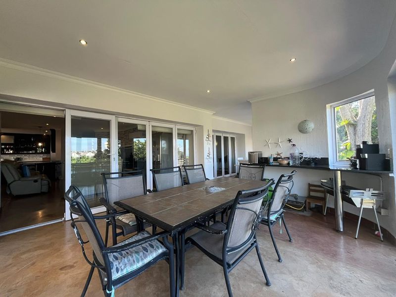 Spacious covered patio featuring concrete flooring, recessed lighting, and a built-in granite bar counter, seamlessly connecting to the interior living space via sliding doors.