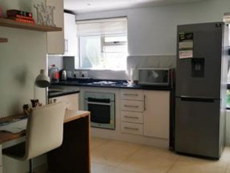 A functional kitchen featuring built-in cabinetry, an integrated oven and hob, tiled flooring, and a window providing natural light.