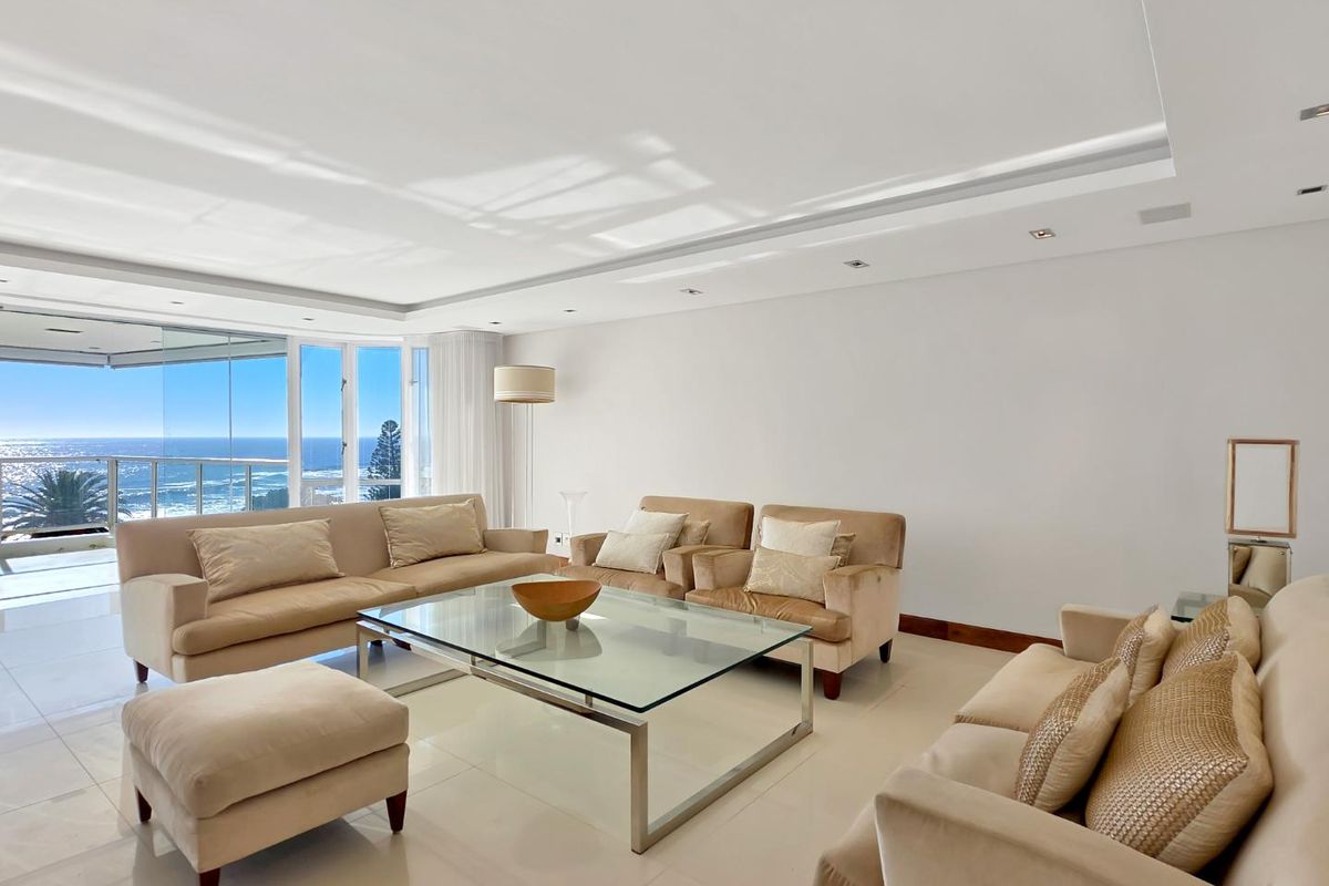 Spacious living room featuring polished tile floors, recessed ceiling lighting, and expansive glass doors offering panoramic ocean views.