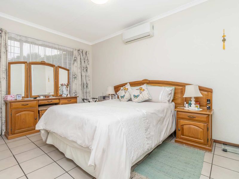 A well-lit bedroom featuring tiled flooring, coving, and a wall-mounted split-system air conditioning unit.