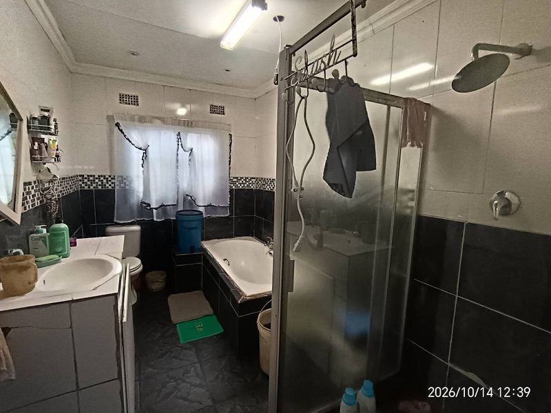 A dated bathroom featuring a built-in vanity, bathtub, and separate shower enclosure with black and white tiled finishes.